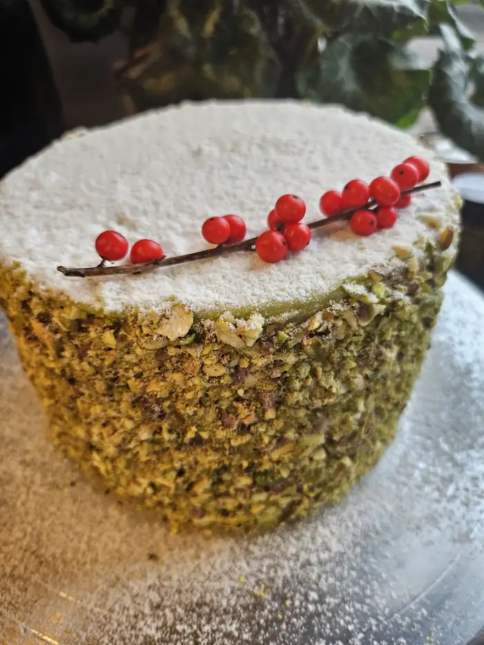 Pistachio cake coated in crushed pistachio with fresh berries